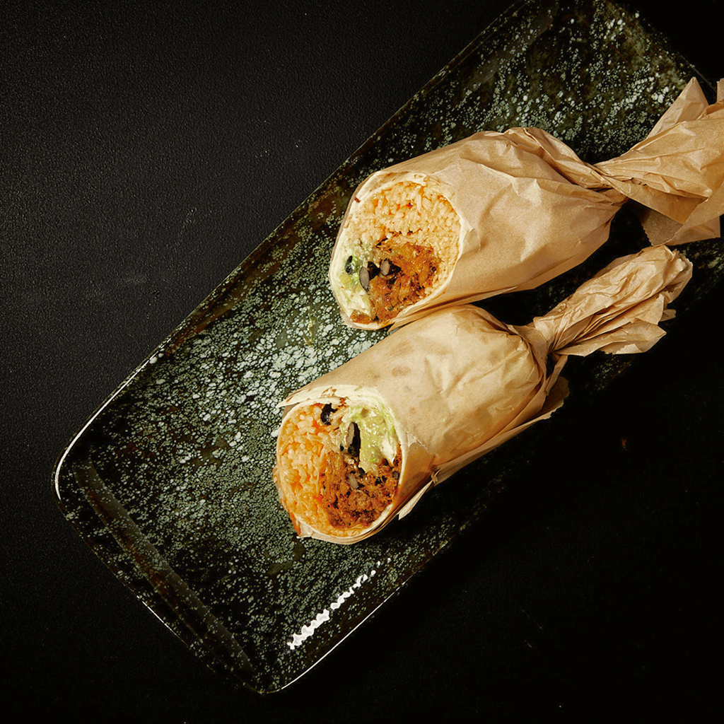 Frisch zubereiteter Burrito Fusion Supreme gefüllt mit würzigen Zutaten, knackigem Gemüse und aromatischer Sauce, serviert auf einem Teller.