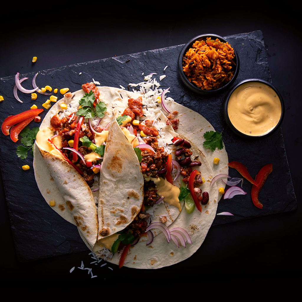 Frisch zubereiteter Burrito Fusion Classico Mexiko gefüllt mit würzigen Zutaten, knackigem Gemüse und aromatischer Sauce, serviert auf einem Teller.