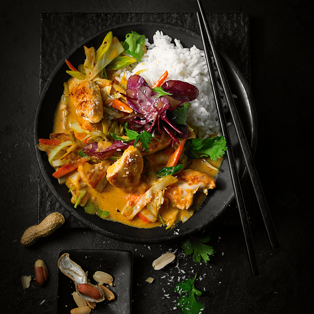 Frisch zubereitete Cocos Chili Boom Wokpfanne mit gebratenem Gemüse, cremiger Kokossauce, feiner Chili-Schärfe und asiatischem Topping in einer Schüssel serviert.